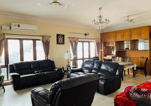 a living room with black leather furniture and a kitchen at Best Individual Home stay Near Apollo Jubilee Hills in Hyderabad