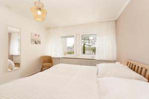 biała sypialnia z 2 łóżkami i oknem w obiekcie Stettiner Straße 55 w mieście Grömitz