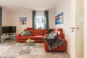 a living room with a red couch and a television at Birkenstraße 6 Haus II Whg1 in Zingst