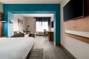 a hotel room with a bed and a living room at La Quinta by Wyndham Stephenville in Stephenville