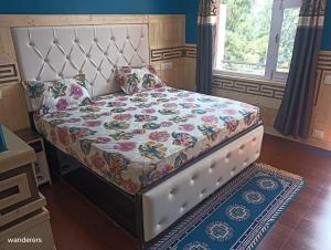 a bed with a floral comforter and pillows on it at Wanderers Homestay -All mountain facing rooms in Kalpa