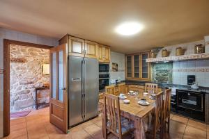 a kitchen with a wooden table and a stainless steel refrigerator at Entre Pedra e Mar by Serendipia Turismo in Goyanes