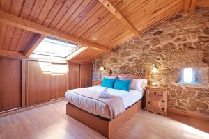 a bedroom with a bed and a stone wall at Entre Pedra e Mar by Serendipia Turismo in Goyanes