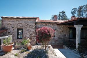 a stone house with a tree in front of it at Entre Pedra e Mar by Serendipia Turismo in Goyanes