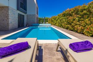 een zwembad met paarse kussens naast een huis bij Apartman SIORA in Njivice