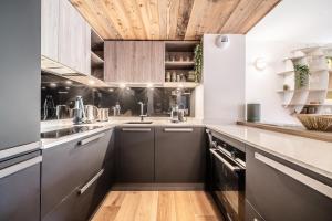 a kitchen with black cabinets and a wooden ceiling at Apartment Colibri Les Gets - by EMERALD STAY in Les Gets
