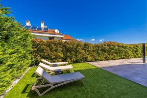 een witte stoel en een bank in een tuin bij Apartman SIORA in Njivice