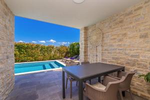 een terras met een tafel en stoelen en een zwembad bij Apartman SIORA in Njivice +15 foto's