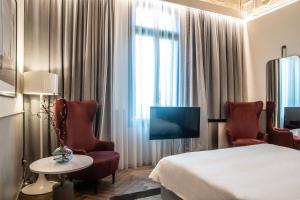 een hotelkamer met een bed en twee stoelen en een televisie bij Radisson Collection Hotel, Palazzo Nani Venice in Venetië
