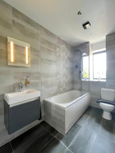 a bathroom with a tub and a sink and a toilet at Luxury Norwich City Centre Apartment - Free Parking in Norwich