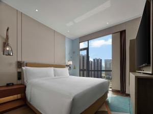 um quarto com uma cama grande e uma janela grande em Doubletree By Hilton Yantai Golden Coast Hotel & Suites em Yantai