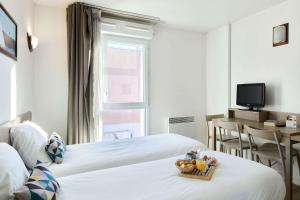 ein Hotelzimmer mit 2 Betten und einem Tisch in der Unterkunft Comfort Aparthotel Versailles, St Cyr l'Ecole in Saint-Cyr-lʼÉcole