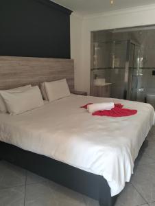 a large white bed with a red robe on it at Sunrise Boutique Hotel in eMalahleni