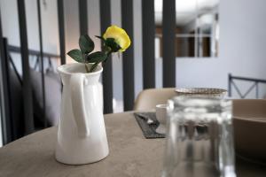 a white vase with a yellow flower in it on a table at ANASTASIA in Makri