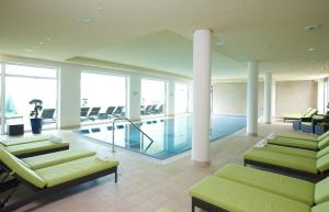eine große Lobby mit Pool und Stühlen in einem Gebäude in der Unterkunft Seehotel Fleesensee in Göhren-Lebbin