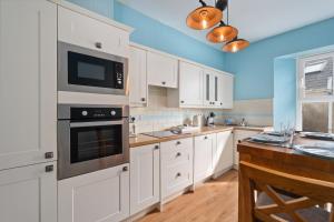 a kitchen with white cabinets and a stove top oven at Kemendine Harbour View in Tenby