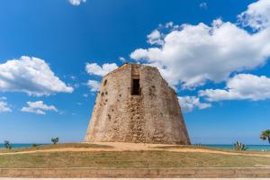 una torre de piedra en una colina con un cielo azul en Antica Gremar en Torre Mozza