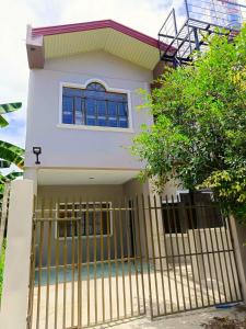 una casa blanca con una puerta delante de ella en HOST HOMES-SANDY LANE en Tacloban