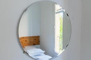um espelho redondo numa parede branca com uma janela em Verdi 254 em Barcelona