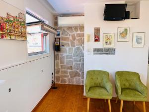 ヴィラ・ノヴァ・デ・ガイアにあるDouro River Apartmentsの緑の椅子2脚とテレビが備わる客室です。