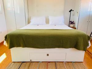um quarto com uma cama grande e um cobertor verde em Douro River Apartments em Vila Nova de Gaia