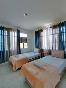 two beds in a room with blue curtains at HOST HOMES-SANDY LANE in Tacloban
