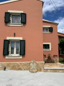 a pink house with green shutters on it at Spitaki in Alepou
