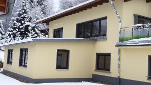 a yellow house with a balcony in the snow at Single Fewo scheiter beck in Feldberg