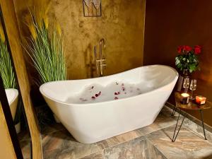 Residence Barrique Valtice في فالتيس: حوض استحمام أبيض في حمام به زهور