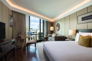 a hotel room with a large bed and a desk and a room at Siam Kempinski Hotel Bangkok - SHA Extra Plus Certified in Bangkok