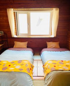 2 Betten in einem Zimmer mit Fenster in der Unterkunft 民泊JOYFUL天然温泉付きログハウス in Shiraoi