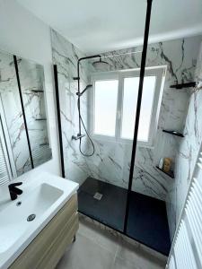 La salle de bains blanche est pourvue d'une douche et d'un lavabo. dans l'établissement Chambre dans appartement élégant proche de Paris, à Suresnes