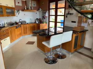 a kitchen with a black counter and white chairs at Keith Lakewood Villa in Balatonfüred