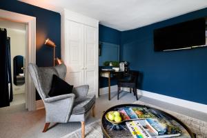 un soggiorno con pareti blu, una sedia e un tavolo di The Old Manse of Blair, Boutique Hotel & Restaurant a Blair Atholl