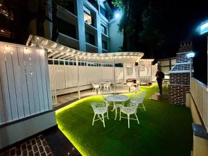 a patio with a table and chairs on the grass at Indraprastha Resort Dalhousie in Dalhousie