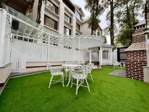 a patio with a table and chairs on the grass at Indraprastha Resort Dalhousie in Dalhousie