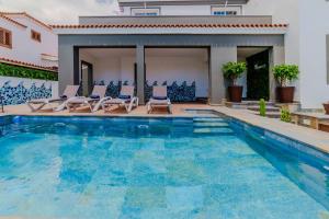 a swimming pool with chairs and a house at Villa in south of Tenerife in Arona