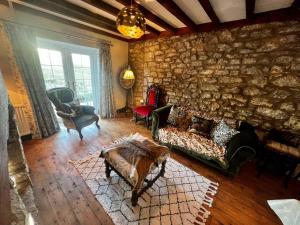 a living room with a couch and a stone wall at 17th century cottage on farm in Vale of Glamorgan in Bonvilston