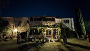 uma antiga casa de pedra com um quintal iluminado à noite em Residenza Santa Maria In Borraccia em Magliano in Toscana