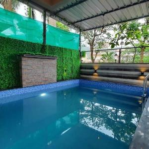 een leeg zwembad met een groene muur bij Ivy Tungarli Dream Villa (4 BHK - Indoor Pool), Lonavala in Lonavala
