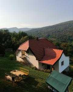 une petite maison blanche avec un toit rouge et une table dans l'établissement Simina kuća, à Bajina Bašta