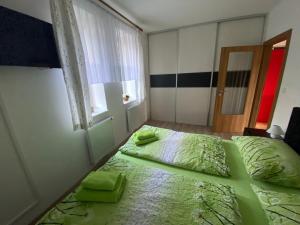 um quarto com uma cama com lençóis verdes e uma janela em Apartmán Verča Riviera Lipno 510 em Lipno nad Vltavou