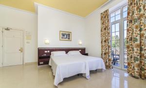 a bedroom with a white bed and a large window at Globales Reina Cristina in Algeciras