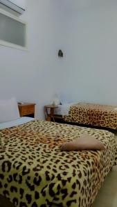 a bedroom with two beds with leopard print sheets at TIRIKA Hôtel La Gazelle in Zemmour Touirza