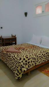 a bed in a room with a leopard print blanket at TIRIKA Hôtel La Gazelle in Zemmour Touirza