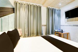 um quarto com uma cama, uma televisão e cortinas em OYO Hotel Diamond Residency em Mumbai