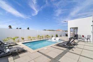 een patio met een zwembad en tuinmeubilair bij Tanki Leendert 43K in Oranjestad