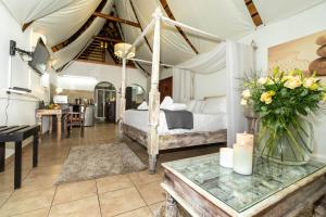 1 dormitorio con 1 cama y 1 mesa con flores en Bolivia Lodge, en Polokwane