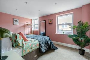 een slaapkamer met roze muren en een bed en een plant bij Central-Few Steps from Brighton Beach by Creatick in Brighton & Hove