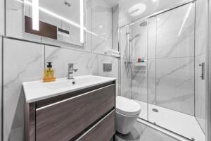 La salle de bains blanche est pourvue d'un lavabo et d'une douche. dans l'établissement Serviced Apartment Golders Green Near Central London- 3, à Londres